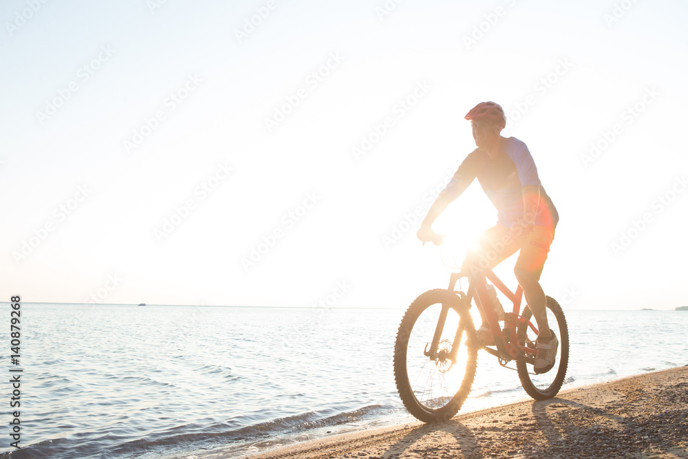 Fototapeta premium Man riding a mountain bike on the beach