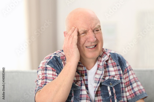 Senior man suffering from headache at home