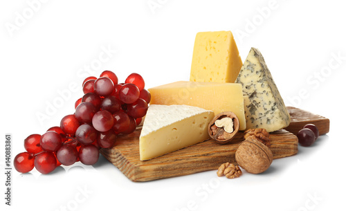 Board with assortment of delicious cheese, grape and nuts on white background