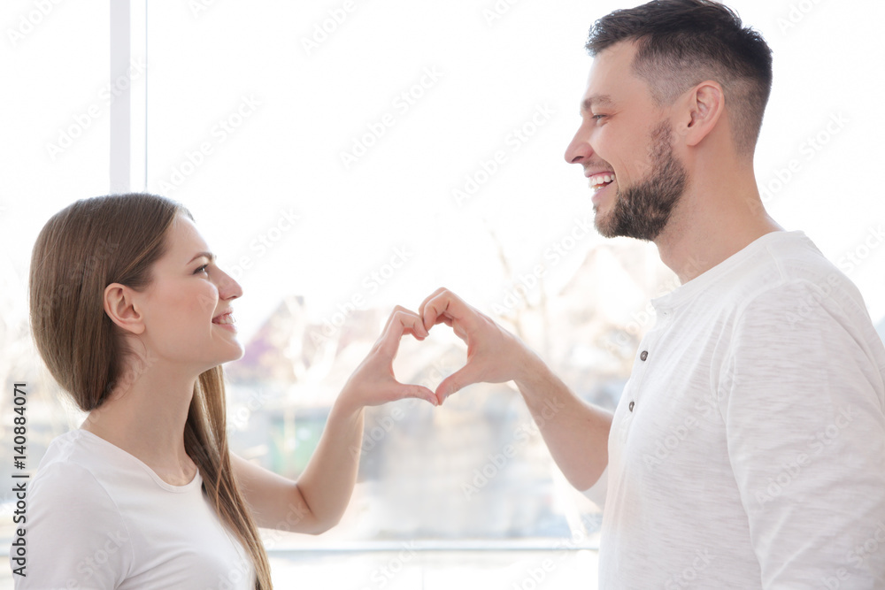 Happy young couple making heart with their hands at home Happy young couple making heart with their hands at home
