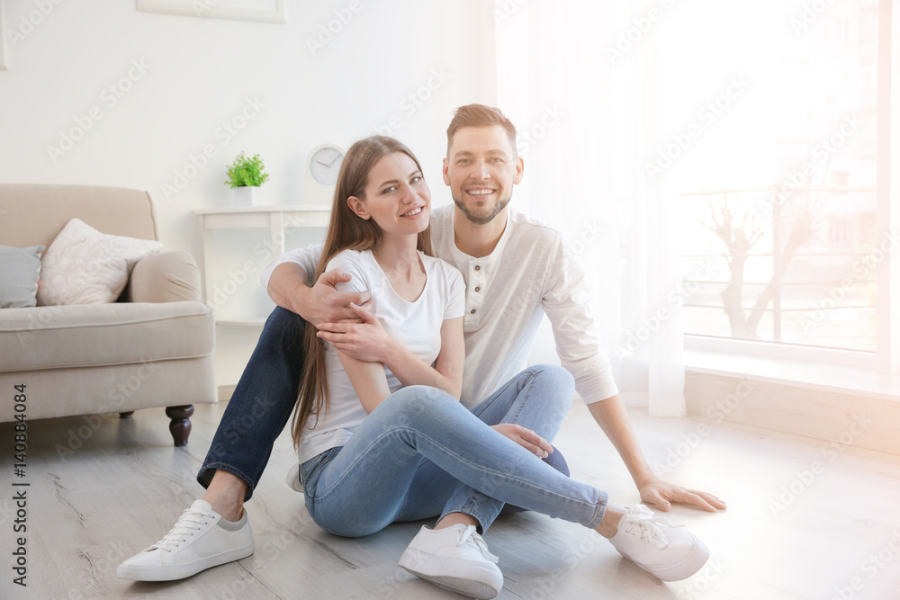 Happy young couple sitting on floor at home