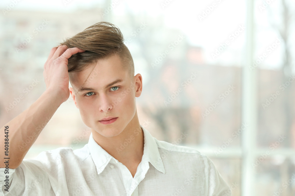 Handsome young man posing on window background