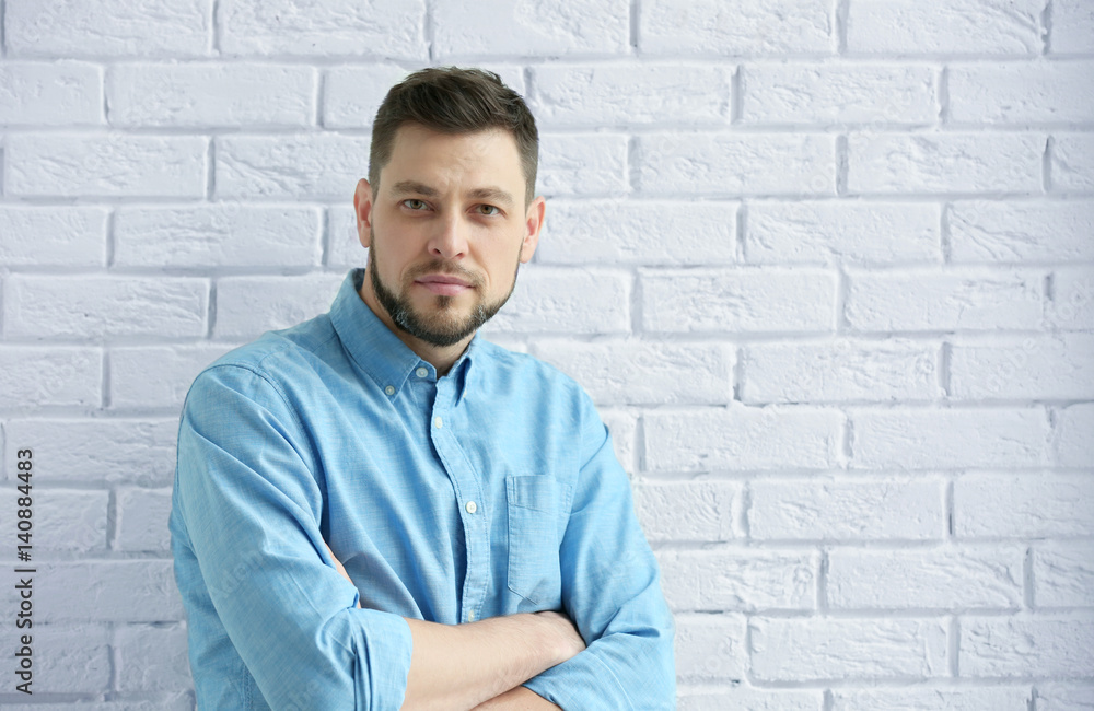 Handsome young man posing on white brick wall background Handsome young man posing on white brick wall background