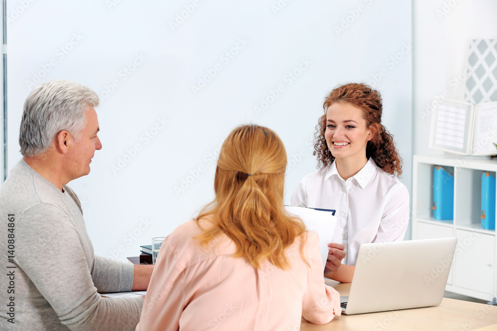 Obraz premium Middle aged couple signing contract at insurance agency office