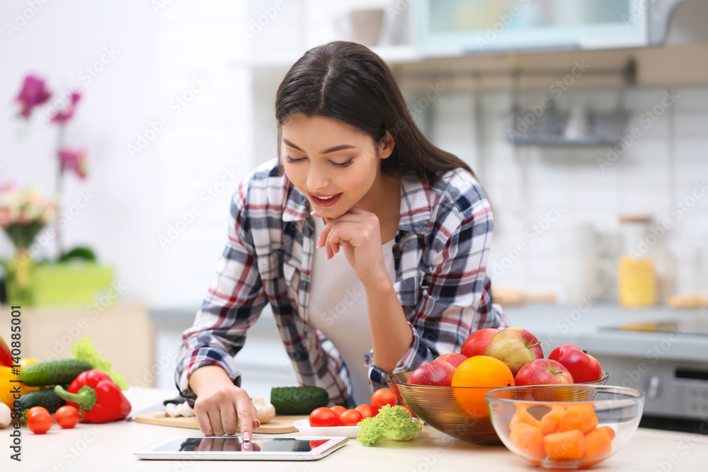 Beautiful young woman with tablet computer in kitchen Beautiful young woman with tablet computer in kitchen