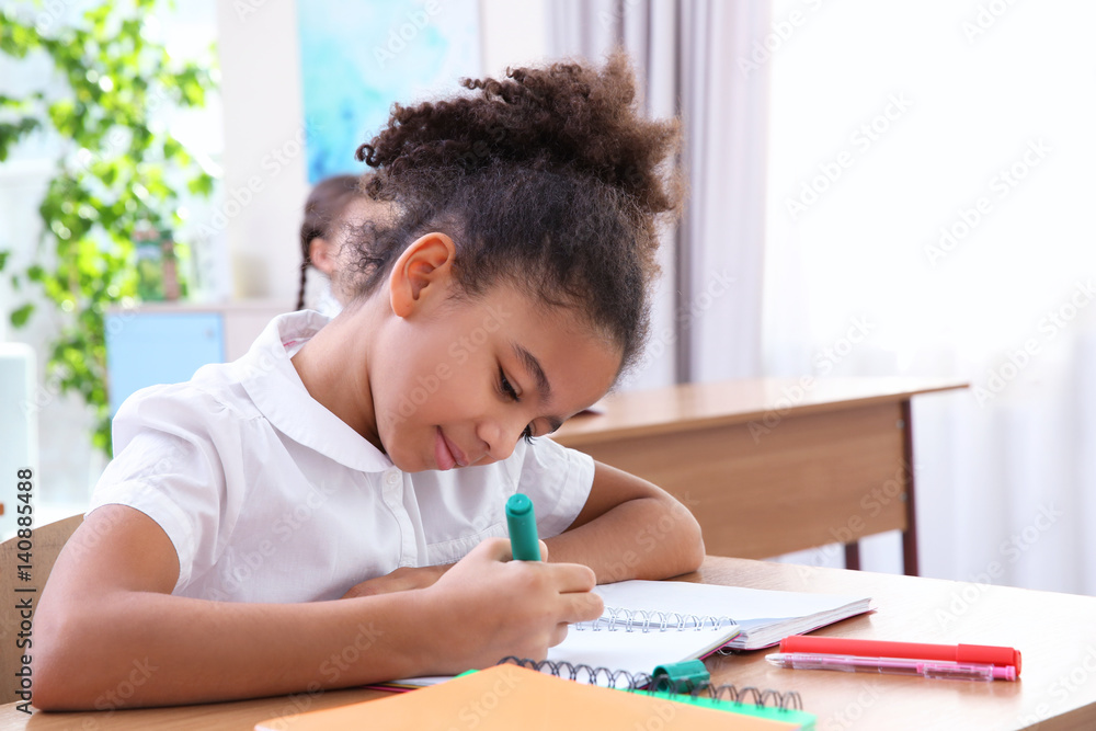 Beautiful elementary schoolgirl studying in classroom Beautiful elementary schoolgirl studying in classroom
