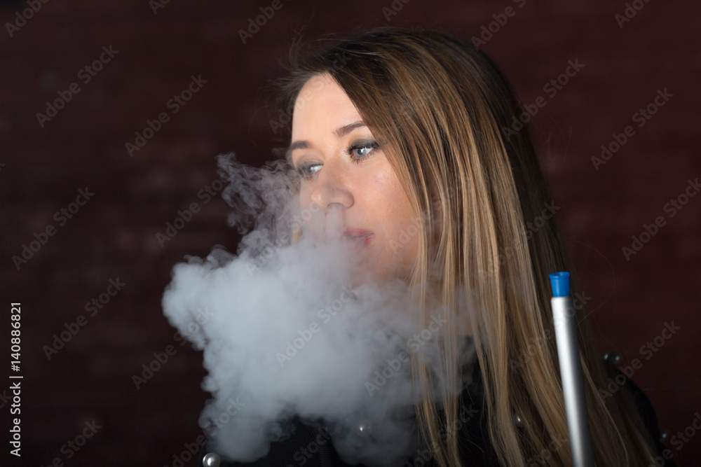 Young, beautiful girl smokes a hookah