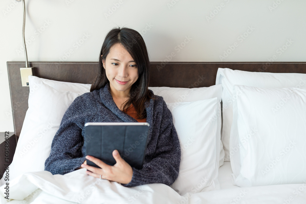 Woman using digital tablet and lying on bed Woman using digital tablet and lying on bed