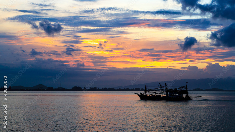 Silhouette of fishing boats with bursting cloud during Sunrise in background
