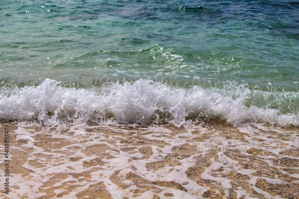 Sea with white wave splashing over beach. Waving sea. Clear turquoise blue sea water over sand beach. Sea with white wave splashing over beach. Waving sea. Clear turquoise blue sea water over sand beach.