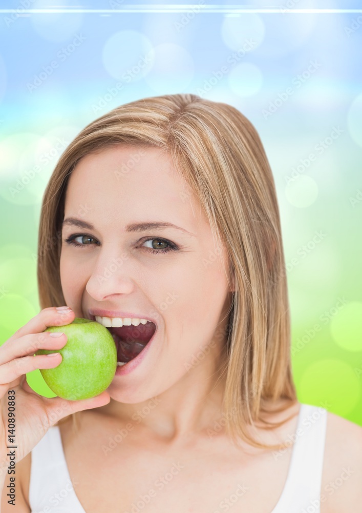 Woman eating an apple against blue green background Woman eating an apple against blue green background