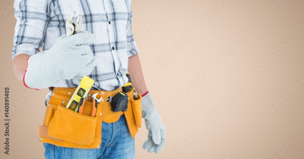 Handy man standing with tools against beige background Handy man standing with tools against beige background