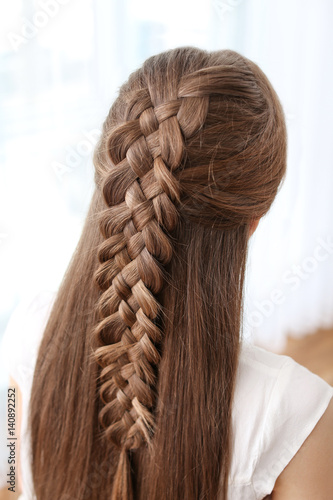 Young beautiful woman with nice braid hairstyle on light background