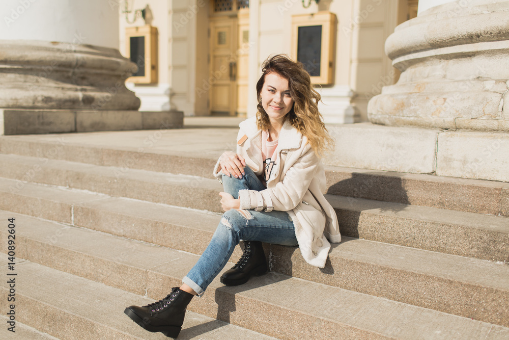 Young beautiful girl sits on the steps of the theater Young beautiful girl sits on the steps of the theater