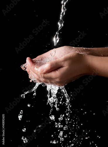 Hand and splashing water on black background