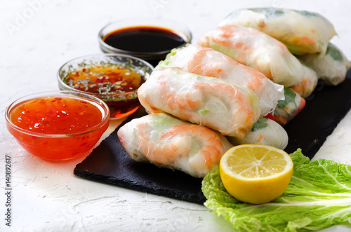 Vietnamese spring rolls - rice paper, lettuce, salad, vermicelli, noodles, shrimps, fish sauce, sweet chili, soy, lemon, veletables. Copy space. Asian and thai food. Traditional national cuisine.