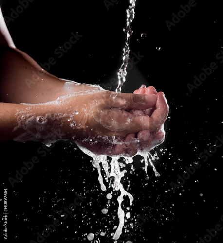 Washing of hands with splashing water on black background