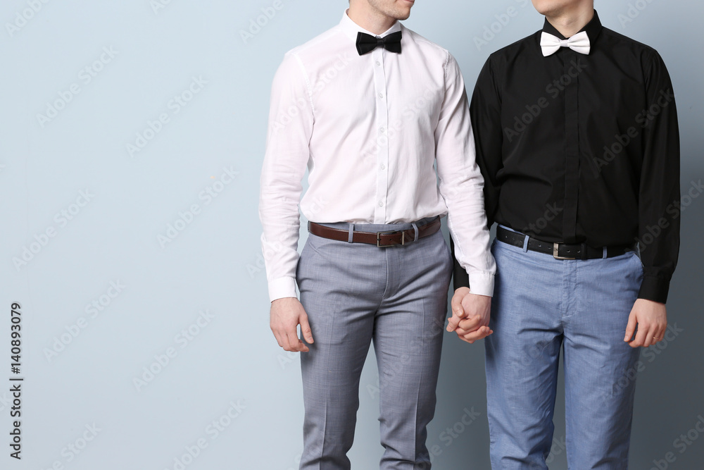 Happy gay couple holding hands together on color background Stock Photo ...