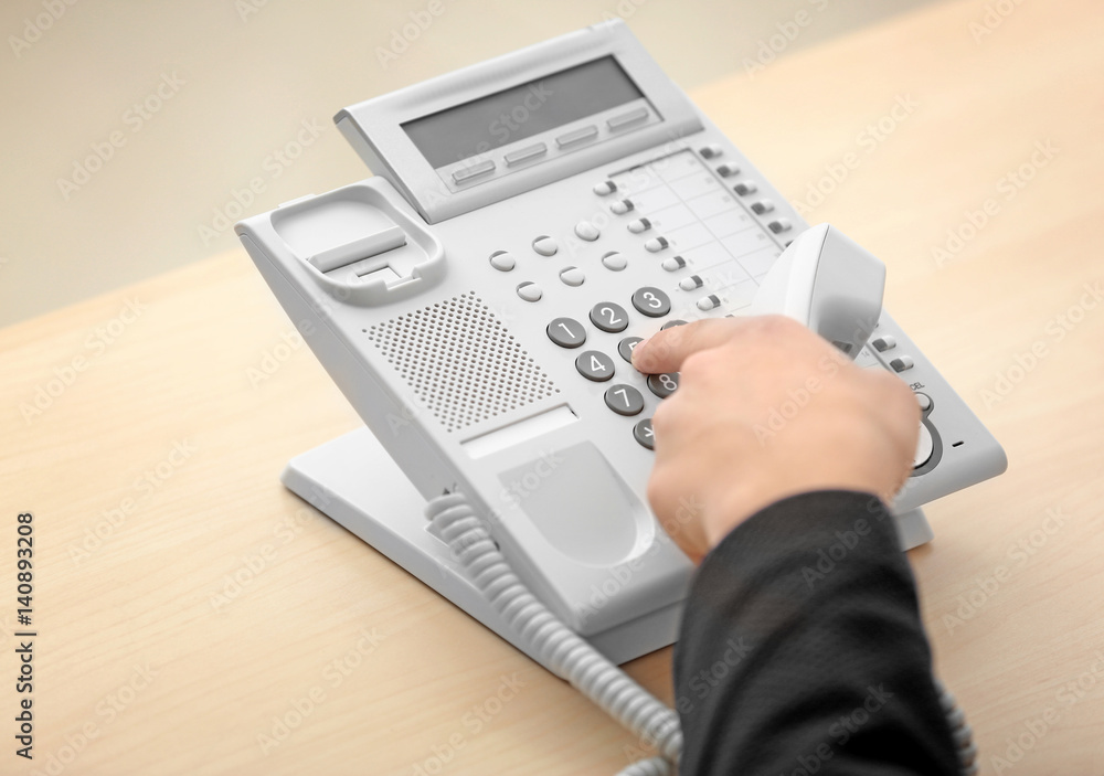 Hand of man dialing telephone number in office Hand of man dialing telephone number in office