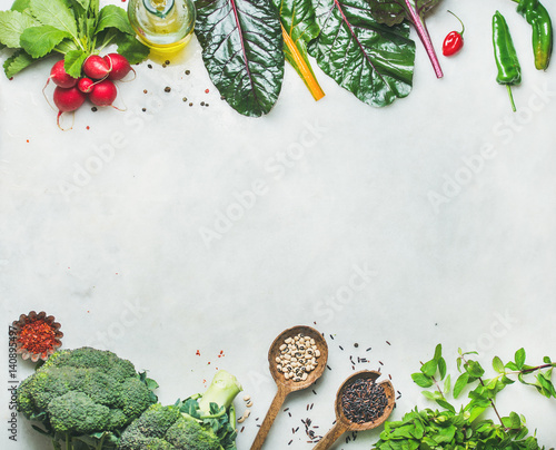 Fresh raw greens, unprocessed vegetables and grains over light grey marble kitchen countertop, top view, copy space. Clean eating, healthy, vegan, vegetarian, detox, dieting food concept