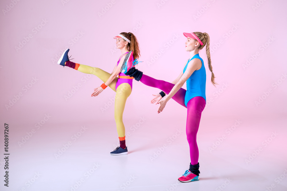 young sporty women doing aerobic exercises on pink