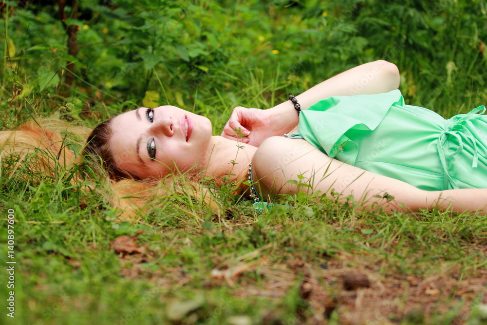 Emotional blonde, smiling in camera, lying on the grass. Emotional blonde, smiling in camera, lying on the grass.