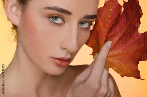 Canvas Print portrait of woman with autumn leaves on yellow background