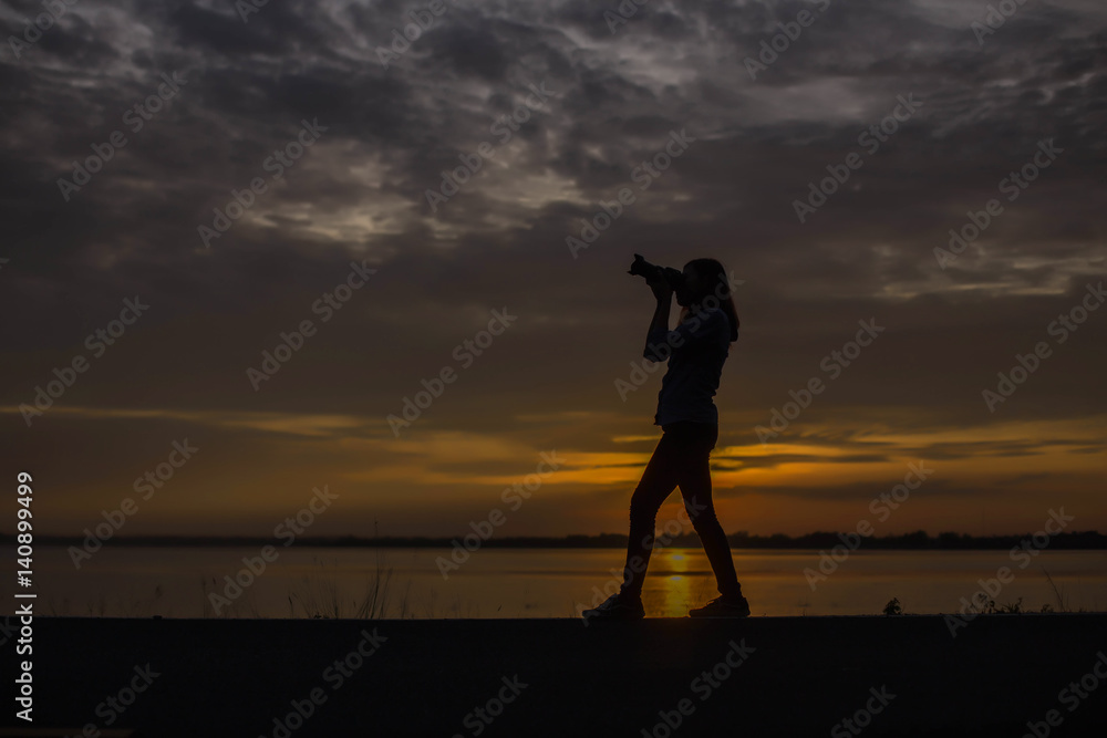 Woman holding a camera on sunset