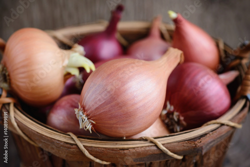 Dry bulb onions in a basket on wooden background