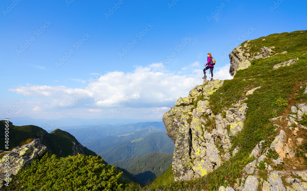 Sporty girl at the edge of precipice high on the mountains.
