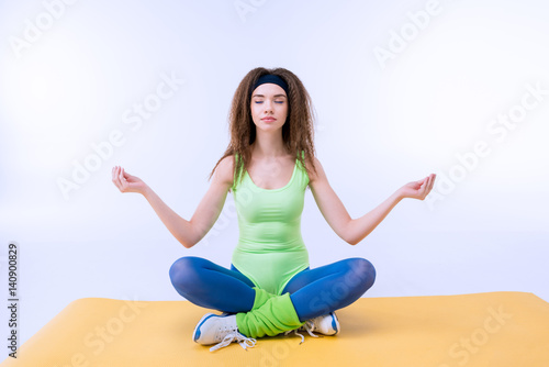 relaxed sporty woman sititng in lotus pose on mat