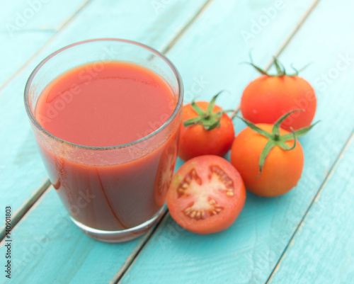 Glass of tomato juice on blue wooden table