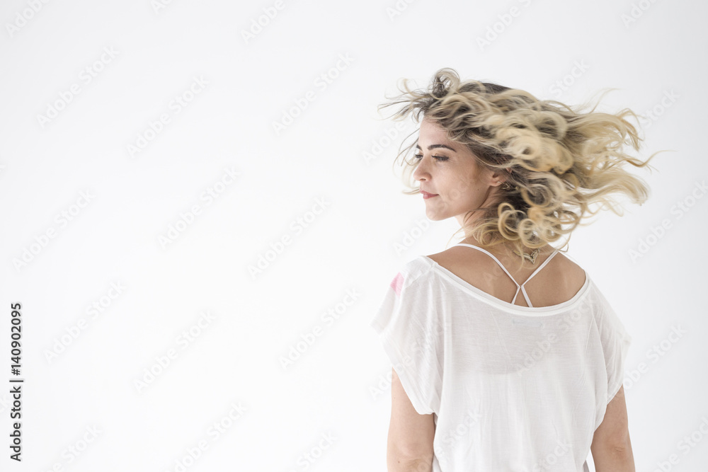 Natural portrait of blonde girl shaking her hair on black background