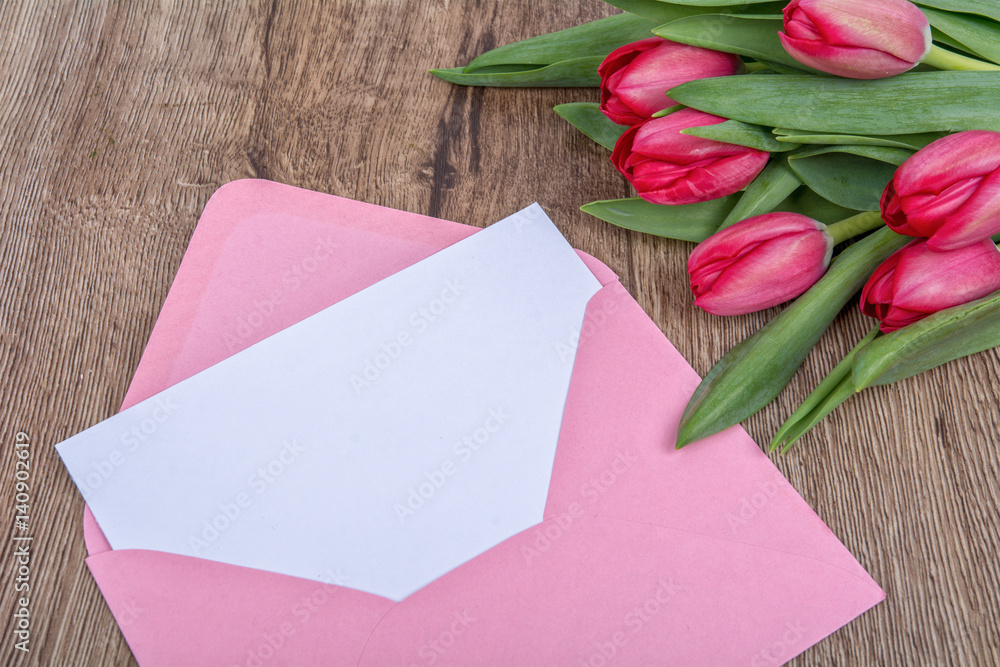 Envelope with sheet of paper and tulips on a wooden background Envelope with sheet of paper and tulips on a wooden background