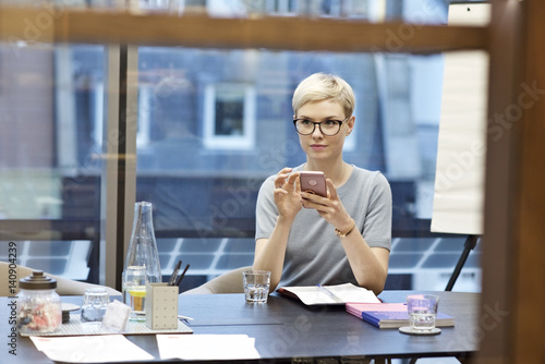 Young caucasian businesswoman in an office using a cell phone