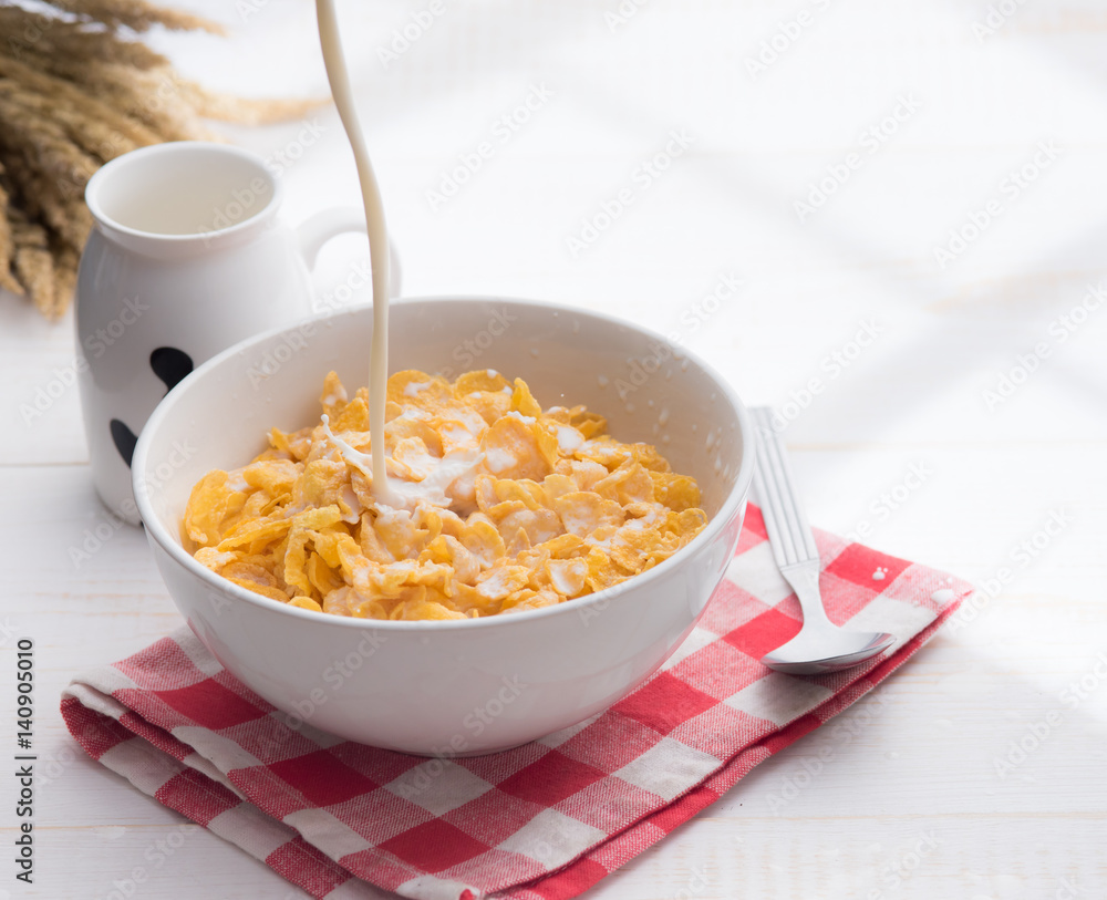 Corn flakes with jug of milk on table wooden,shadows from a window frame Corn flakes with jug of milk on table wooden,shadows from a window frame