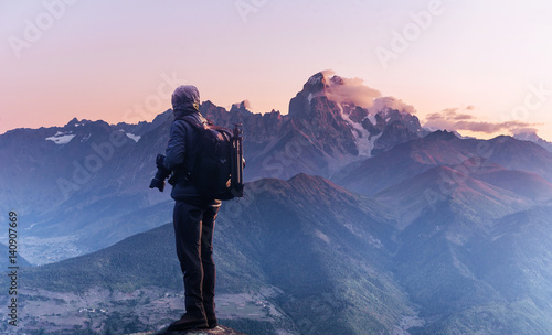 Professional photographer takes photos with big camera on peak of rock