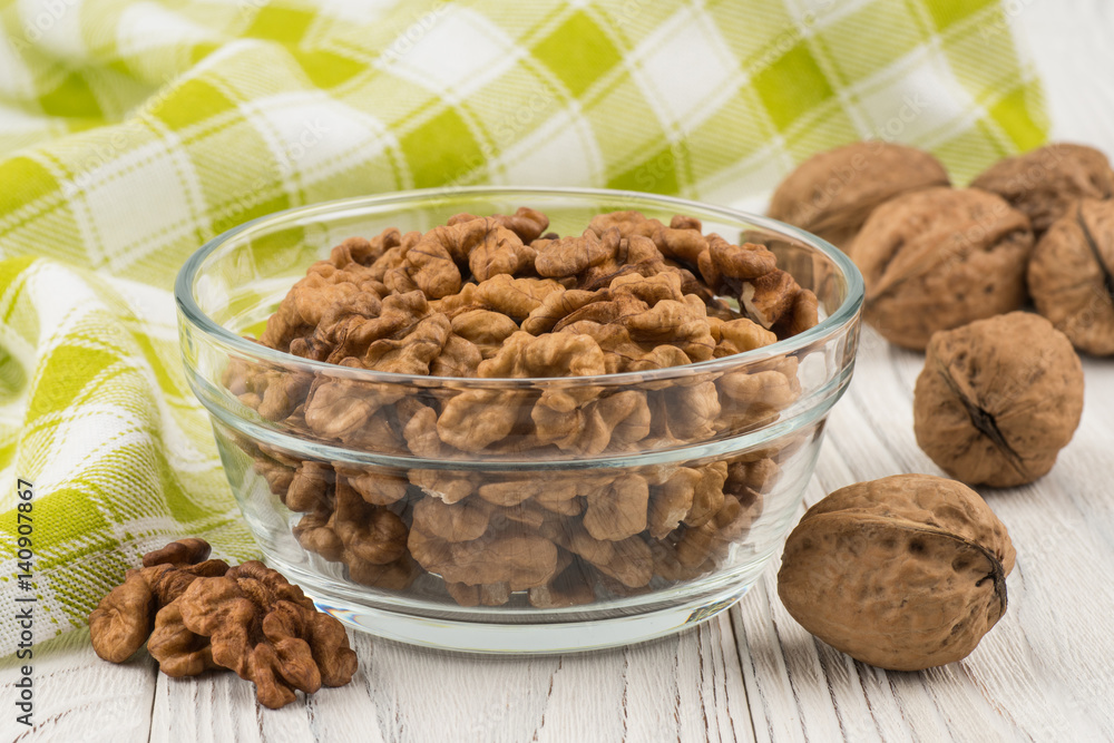 Walnuts in a glass bowl on an old white wooden table. Walnuts in a glass bowl on an old white wooden table.