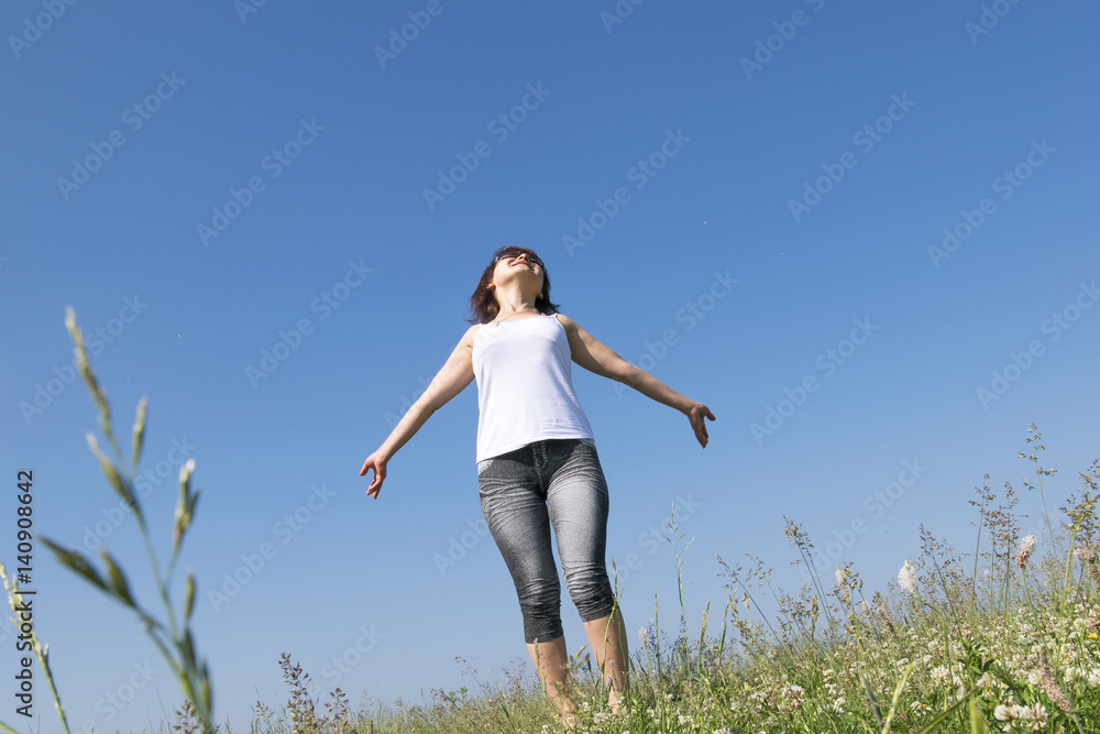 Beautiful brunette girl in a summer field of flowers is charged with energy