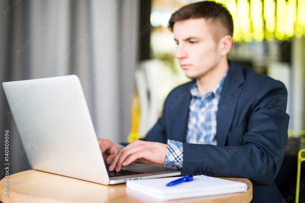 Happy young man works on his laptop to get all his business done early in the morning with his cup of coffee Happy young man works on his laptop to get all his business done early in the morning with his cup of coffee