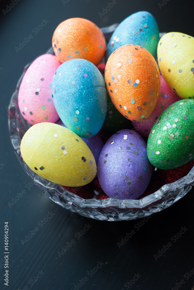 Easter eggs in crystal dishes on a black wooden background,