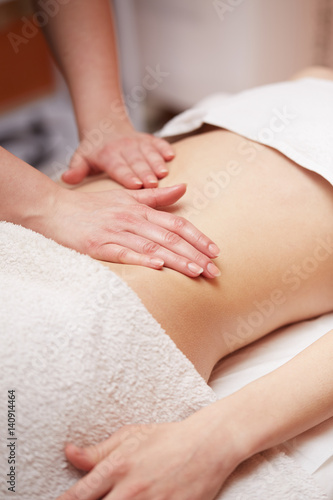A woman receiving a belly massage at spa salon