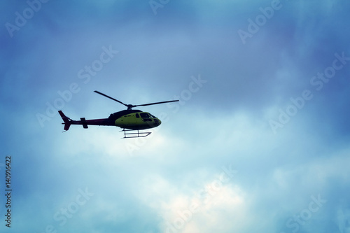 Rotor helicopter flying against the blue sky background