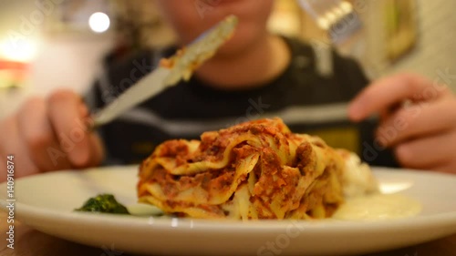 boy is eating a lasagna in a cafe