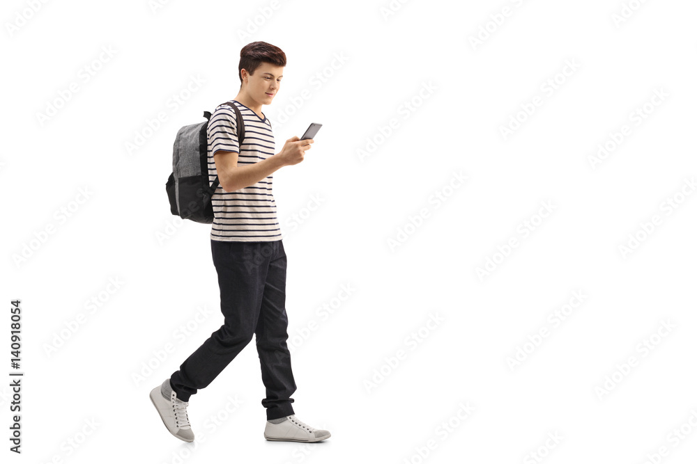 Naklejka premium Teenage student walking and looking at a phone