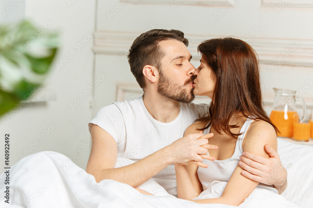 Young adult heterosexual couple lying on bed in bedroom Young adult heterosexual couple lying on bed in bedroom