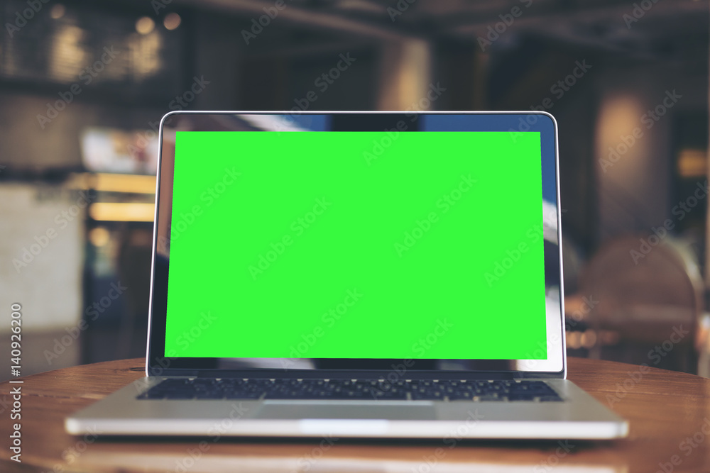Mockup image of laptop with blank green screen on wooden table in vintage cafe Mockup image of laptop with blank green screen on wooden table in vintage cafe