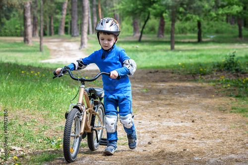 Happy kid boy of 4 years having fun in autumn forest with a bicycle on beautiful fall day. Active child making sports. Safety, , leisure kids concept