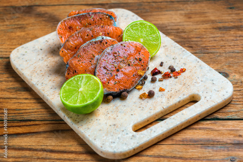 Raw marinated trout fillet on wooden cutting board. Steak of salmom ready to frying photo