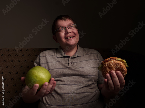 Obraz na plátně Man with big belly thinking of what to eat - apple or burger
